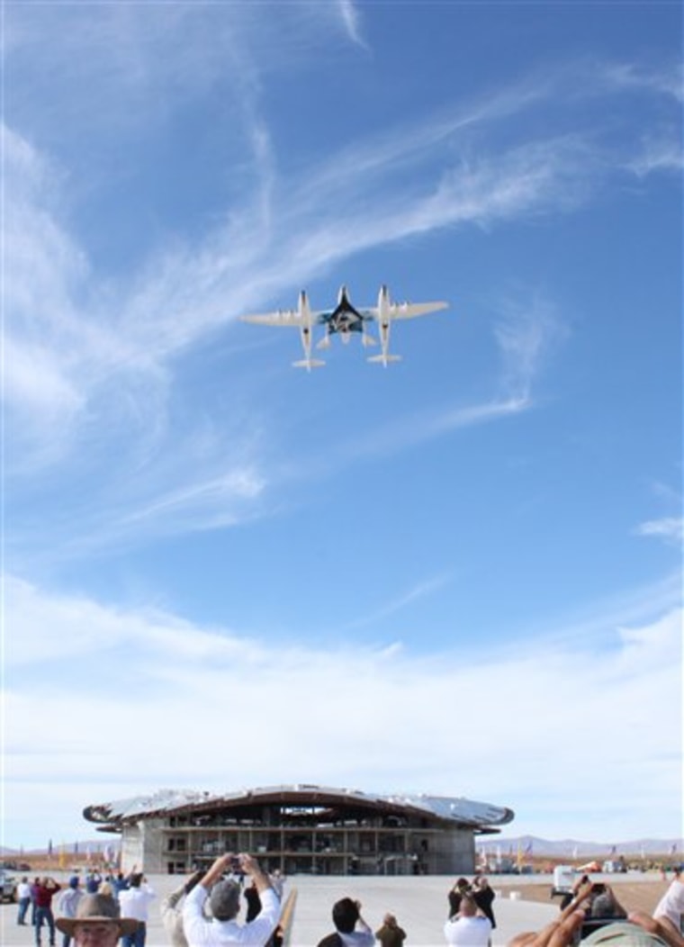 Virgin Galactic's White Knight Two jet-powered carrier aircraft flies over Spaceport America with the SpaceShipTwo rocket plane attached during Friday's dedication ceremony in New Mexico.